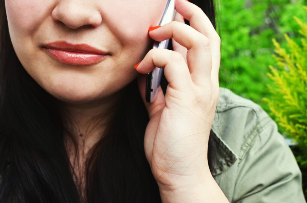 A woman with orange nail polish, talking to someone on the phone