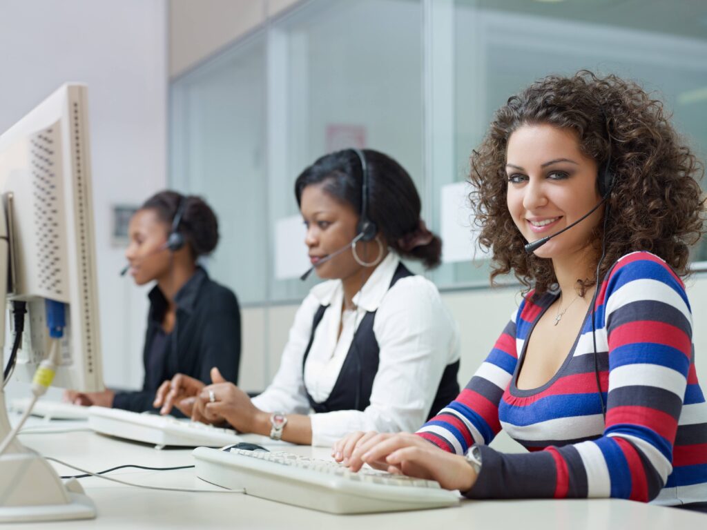 Three women in front of their computers while wearing headphones